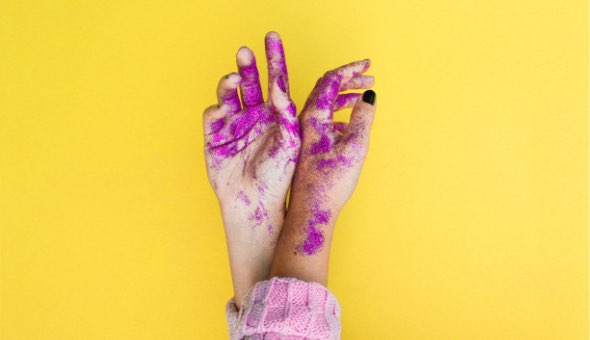 Händer med lila färg på mot gul bakgrund